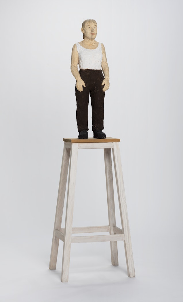 Figura femenina de pie con pantalon café